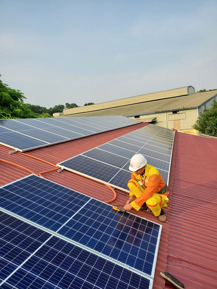 why-choose-us Technician working on solar panel installation on a rooftop under clear sky.