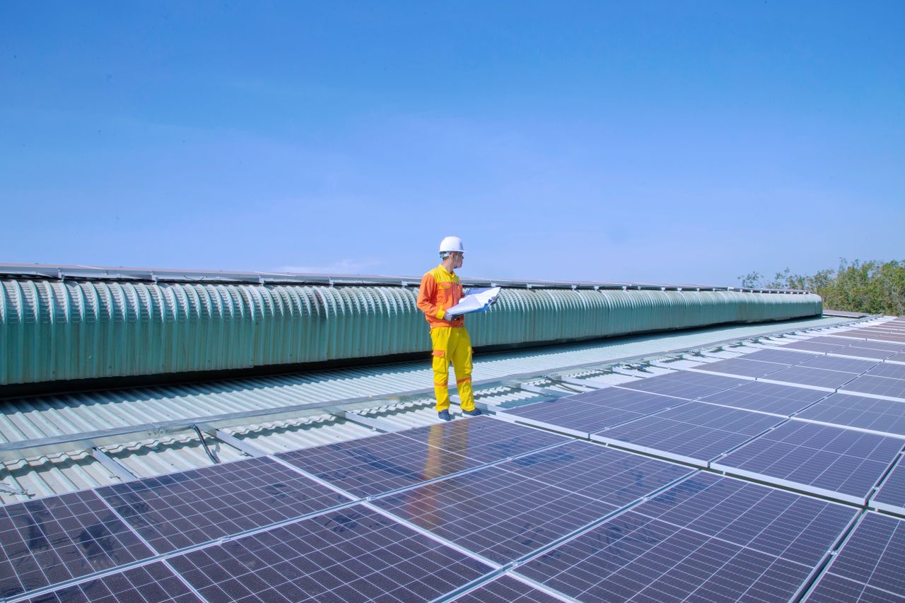 gallery-5 Technician examining solar panels on a rooftop, emphasizing renewable energy.
